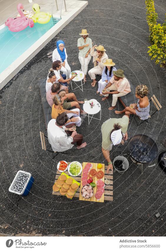 Multiethnic friends gathered for a poolside BBQ party summer bbq gathering outdoor food conversation swimming pool diverse multiethnic group meat vegetables