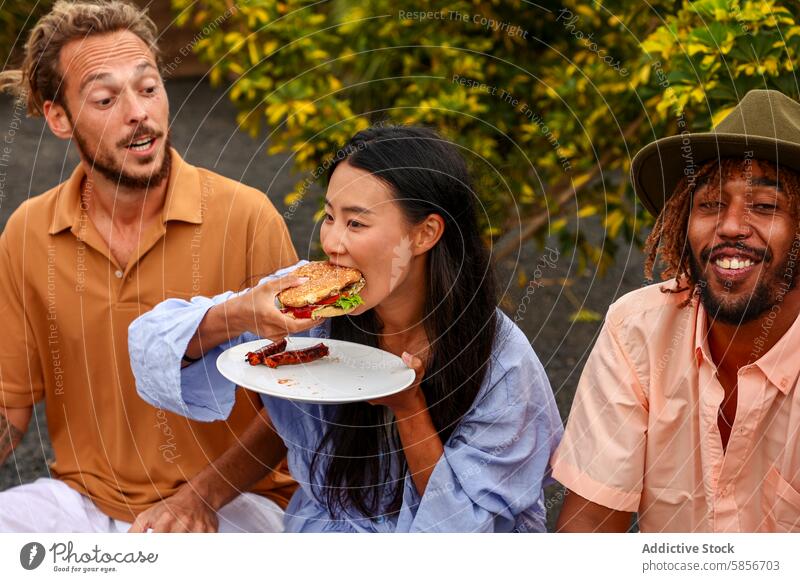 Friends enjoying a BBQ party outdoors with music and food bbq friends burger multiethnic asian woman caucasian man african american man casual smiling