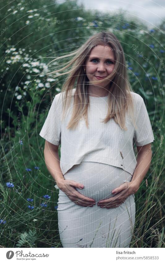 PREGNANT - WINDY - FLOWERS Woman Pregnant pregnancy youthful pretty long hairs windy flowers Smiling expectant Baby bump Stomach Feminine naturally Green