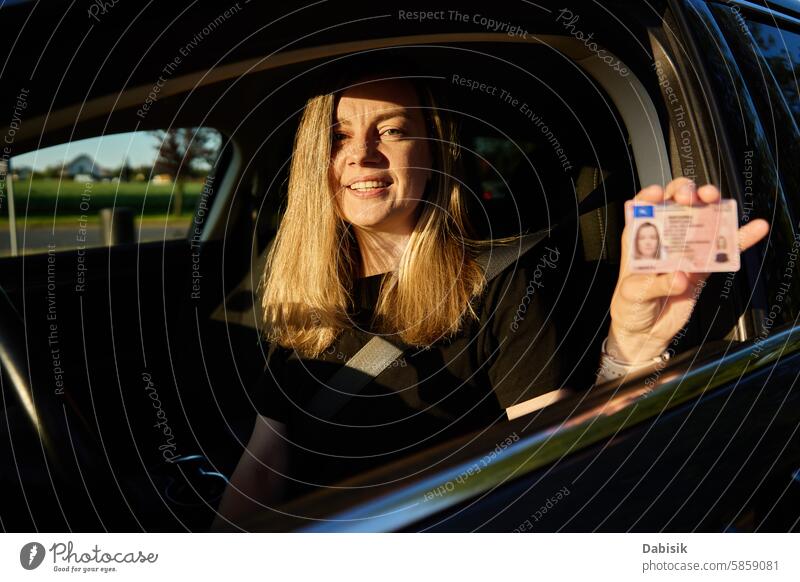 Happy Woman Holding Driver License in Car woman driving license car driver holding happy positive document exam vehicle safety sunset seat joy permit school