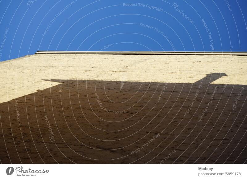 Facade and firewall of an old building in beige and natural colors with shadow and silhouette of the neighboring house against a blue sky in the sunshine in Berger Straße in the Bornheim district of Frankfurt am Main in Hesse