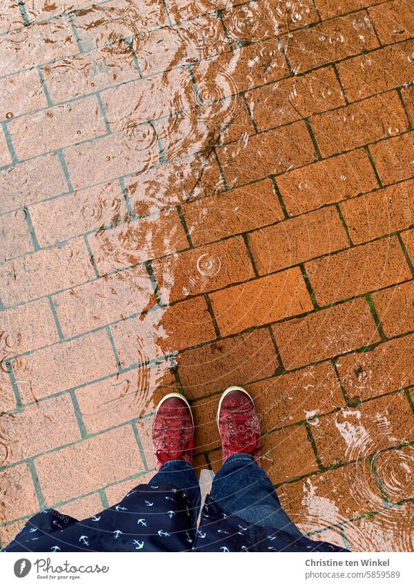 On foot in rainy weather Rain Puddle Wet wet shoes Raincoat raindrops Rainy weather Bad weather Reflection off Paving stone paved Red Blue on foot