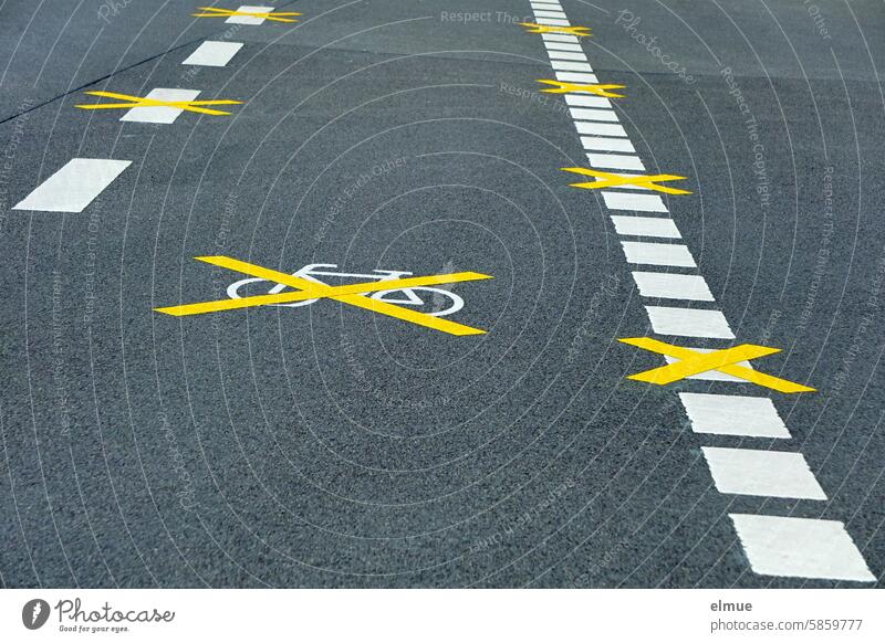 New cycle path on an asphalt road, still invalidated with yellow crosses Cycle path Wheel pictogram void Asphalt Lane markings StVO Pictogram Road marking
