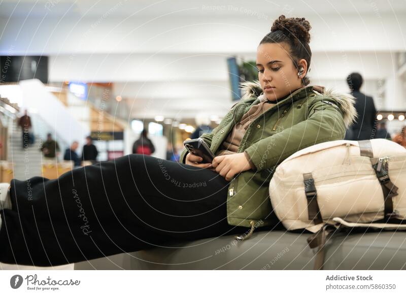 Young Woman Using Smartphone at Airport airport young woman smartphone waiting travel sitting technology passenger female communication mobile phone terminal