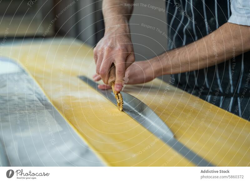 Artisan cutting fresh pasta dough by hand artisan cutter sheet traditional close-up culinary preparation cooking kitchen handmade craft food rolling pin apron