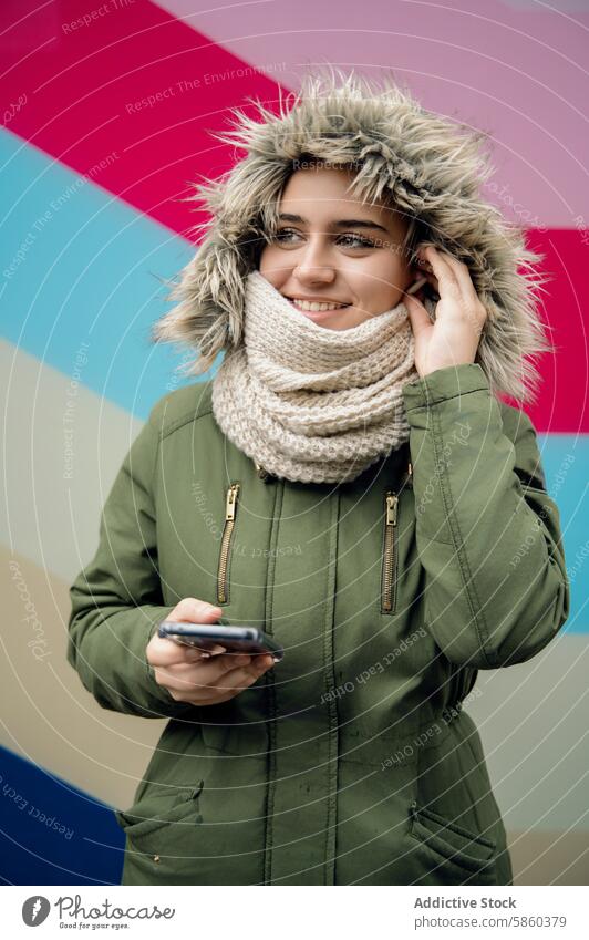 Young woman with smartphone on colorful background winter clothing smiling young adult female technology mobile phone device communication connectivity