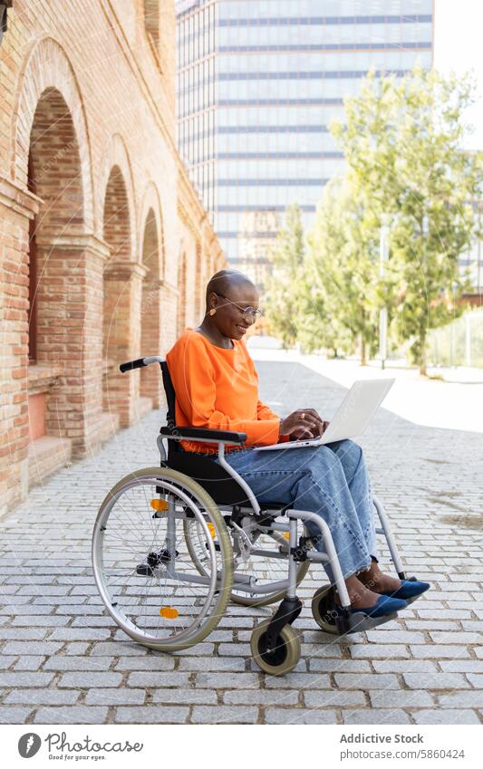 African American woman working from wheelchair in urban setting businesswoman laptop outdoor accessibility inclusivity modern architecture african american