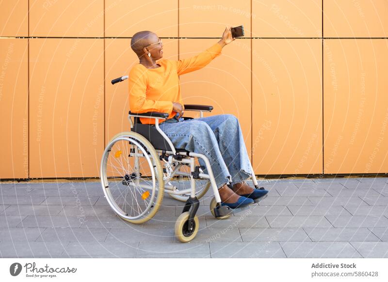 Businesswoman in wheelchair taking a selfie outdoors businesswoman independence technology orange backdrop modern vibrant accessibility mobility inclusive