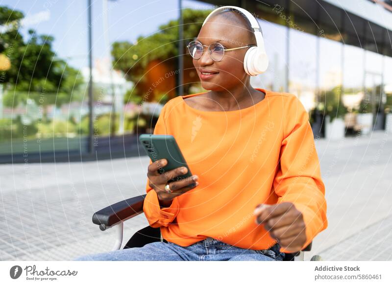 Businesswoman in wheelchair using smartphone outdoors businesswoman urban headphones joy african american black woman ethnic communication accessibility