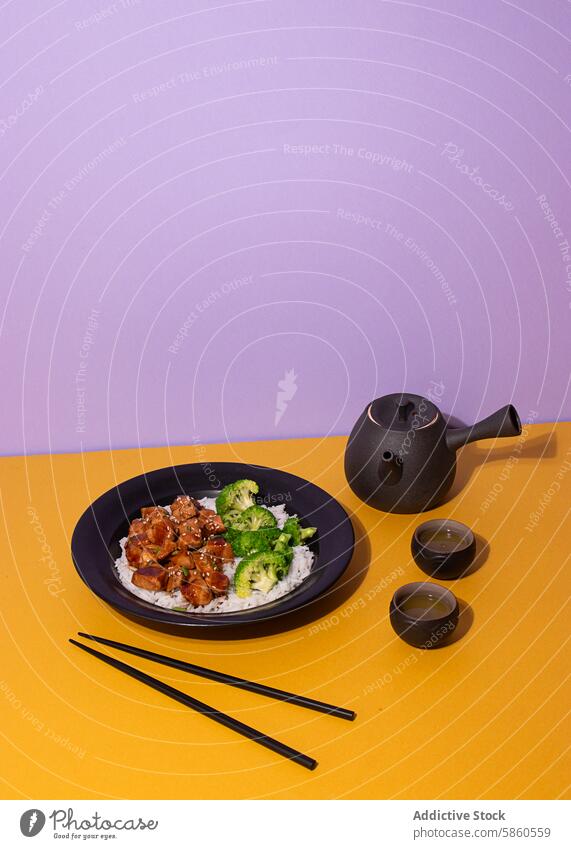 Teriyaki chicken meal with tea set on colorful background appetizing artistic asian beverage black plate broccoli chopsticks presentation crockery culinary