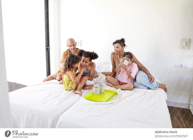 Multiethnic family enjoying breakfast in bed together multiethnic morning bedroom children parents joyful sunlit atmosphere loving warm togetherness bonding