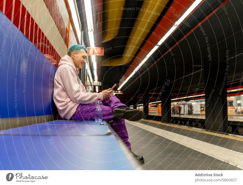 Young man with blue hair using smartphone at subway station young sitting purple outfit colorful platform urban commute technology mobile device casual fashion