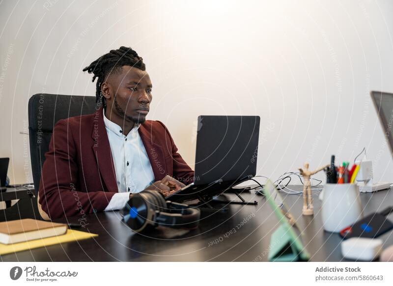 Professional man working on laptop in modern office professional technology business focused desk gadget maroon blazer shirt sitting chair minimalist sleek