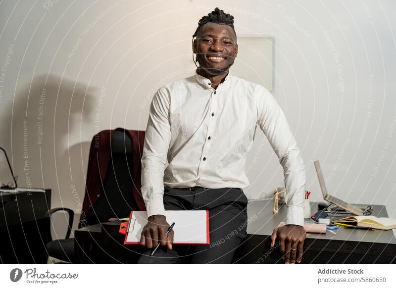 Confident businessman in the office with a smile desk folder professional confident approachable work worker employee job corporate indoors white shirt sitting