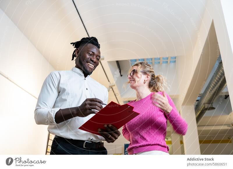 Colleagues discussing work with smiles and a clipboard office colleague discussion smiling man woman professional collaboration modern positive productive