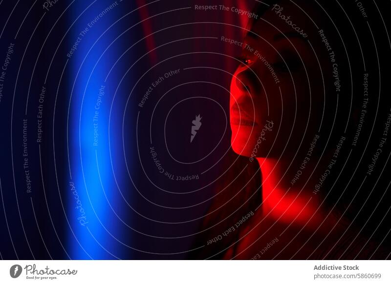 Woman illuminated by vibrant neon lights in dark room woman night contemplative moody glow red blue shadow enigmatic portrait face expression emotion ambiance