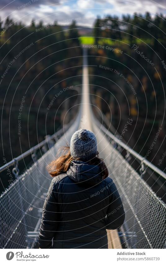 Anonymous woman crossing the Geierlay suspension bridge in Germany geierlay germany autumn walk rope forest picturesque journey travel tourism adventure scenic