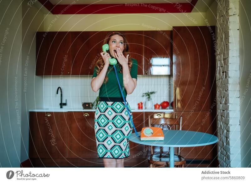 Woman in retro kitchen looking surprised on rotary phone woman 1950s colorful fashion housewife vintage green top patterned skirt talking shocked nostalgic