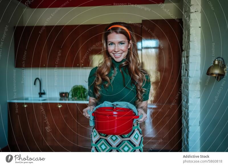 Comical 1950s Housewife in Retro Kitchen Holding Red Pot woman smiling kitchen housewife red pot retro vintage cooking caucasian green top patterned skirt