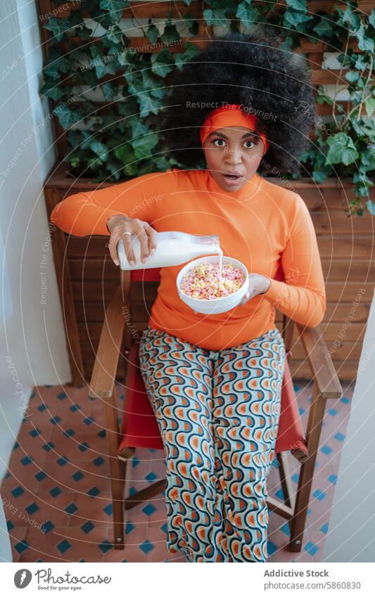 Surprised woman pours milk in cereal in retro outfit colorful surprise expression afro hair african american pouring bowl 70s fashion hairstyle indoor vibrant