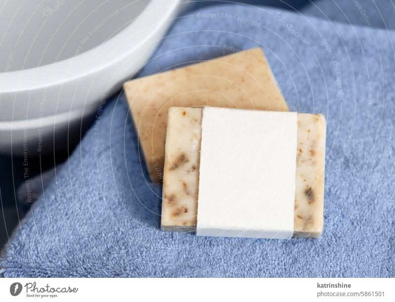 Soap bar with blank label on blue towels near vessel sink in bathroom, packaging mockup soap bar hygiene cosmetic basin paper white close up Brand eco friendly