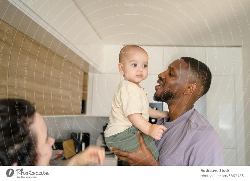 Joyful multiracial family moment in the kitchen african american caucasian toddler man smile modern interaction joyful diverse happiness child father parent