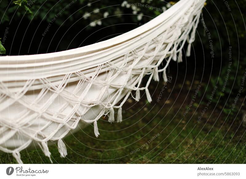 [HH Schregatour24] A cream-white hammock hangs in the garden, someone is obviously lying in it, but you can't see them Garden Hammock White Cords woven Grass