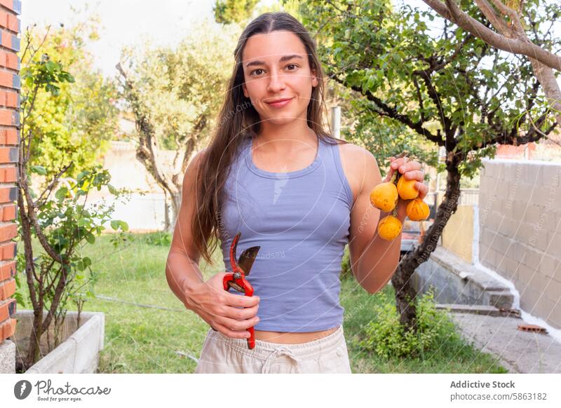 Woman Holding Freshly Picked Fruits and Pruning Shears in Garden woman garden loquats picking fruit pruning shears fresh harvest outdoor horticulture gardening