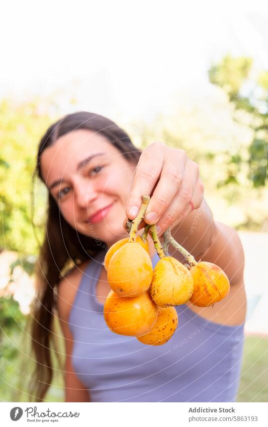 Woman Proudly Displaying Freshly Picked Fruits from Garden woman garden loquats picking fruit orange fresh harvest outdoor horticulture gardening care foliage