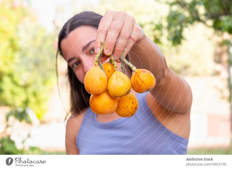 Woman Proudly Displaying Freshly Picked Fruits from Garden woman garden loquats picking fruit orange fresh harvest outdoor horticulture gardening care foliage