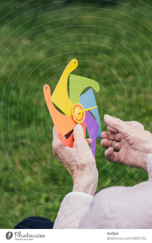 Crafting utensils for a wind turbine in the hands of a senior citizen Handicraft Pinwheel variegated Senior citizen Leisure and hobbies Multicoloured Paper