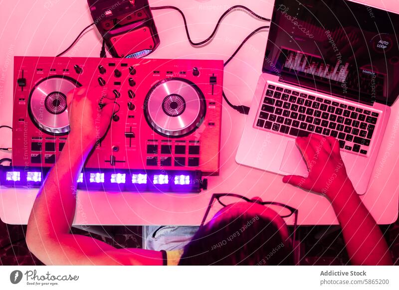 DJ mixes tracks on modern equipment under pink lights dj music controller laptop nightclub hand disc jockey turntable knob button party event sound