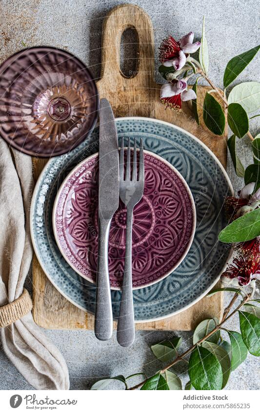 Elegant table setting with feijoa and unique floral decoration fruit ceramic plate rustic wood cutting board texture purple blue silverware knife fork napkin