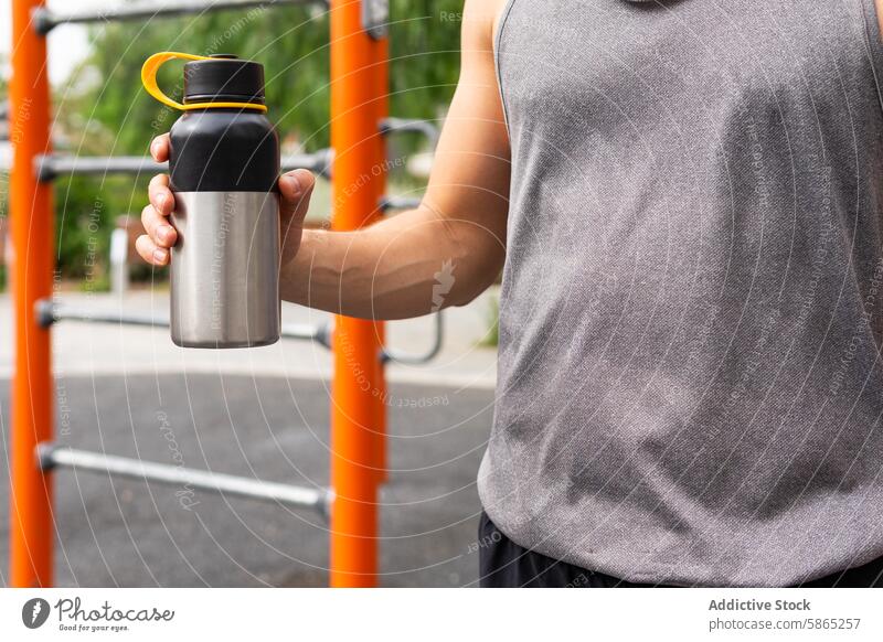 Unrecognizable man holding a metal water bottle at a fitness park healthy lifestyle outdoor poblenou active steel stainless tank top grip anonymous summer