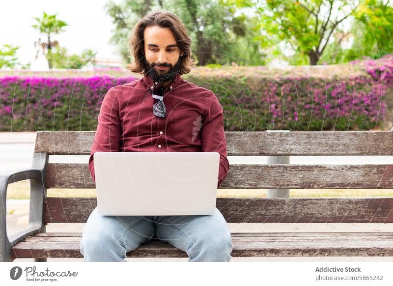 Man working on laptop in park at Poblenou, Barcelona man bench poblenou barcelona outdoor technology remote casual connectivity internet greenery flower urban