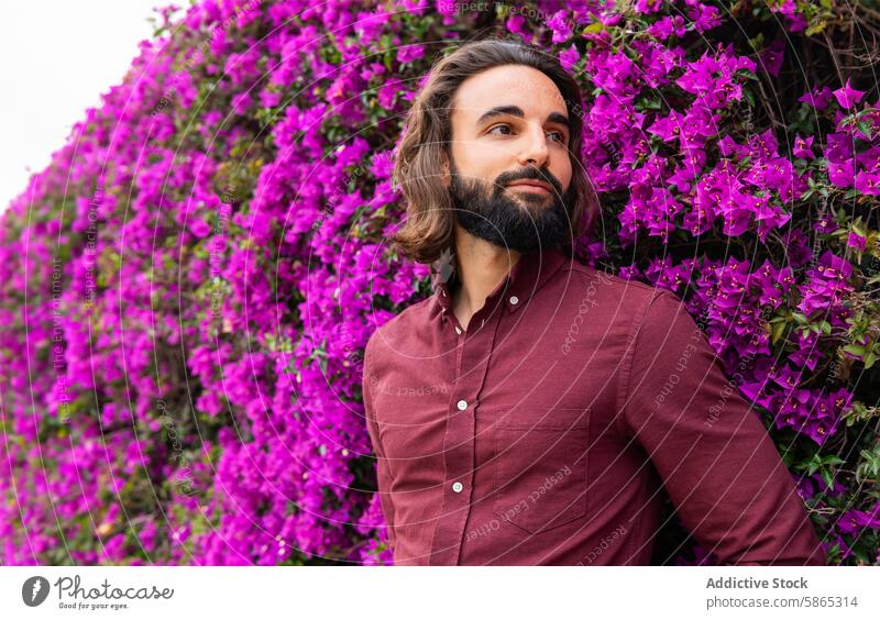 Man in burgundy shirt posing by vivid purple flowers man bougainvillea style serenity lifestyle pose beard outdoor nature plant bloom spring facial hair