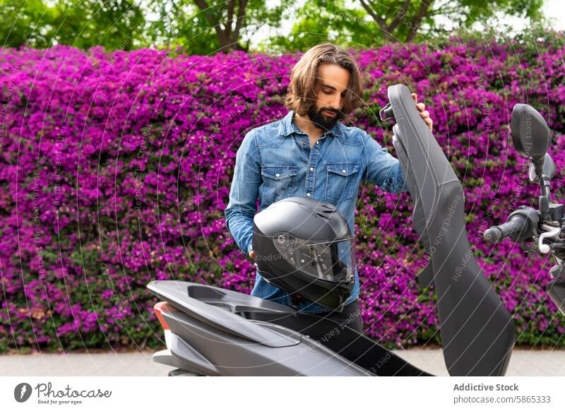 Man preparing for a scooter ride in Poblenou man helmet safety outdoor bougainvillea purple flowers lifestyle poblenou urban leisure sport young stylish denim