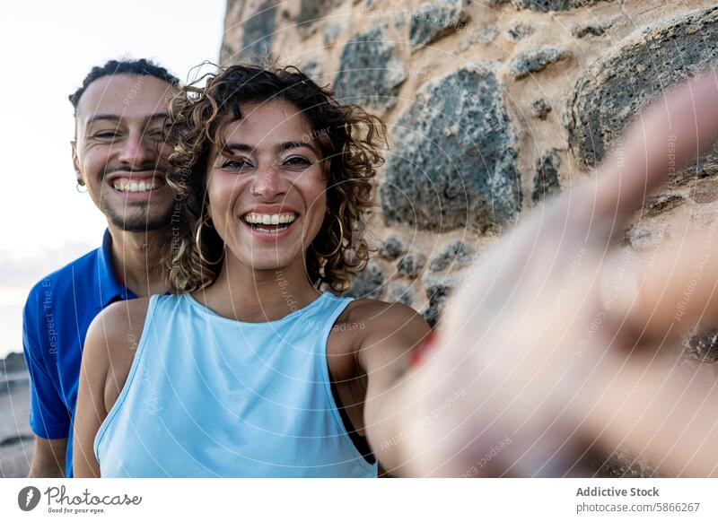 Joyful couple taking a selfie with a coastal background woman smile dreadlocks cheerful joy expression pleased rugged daylight outdoor landscape candid genuine