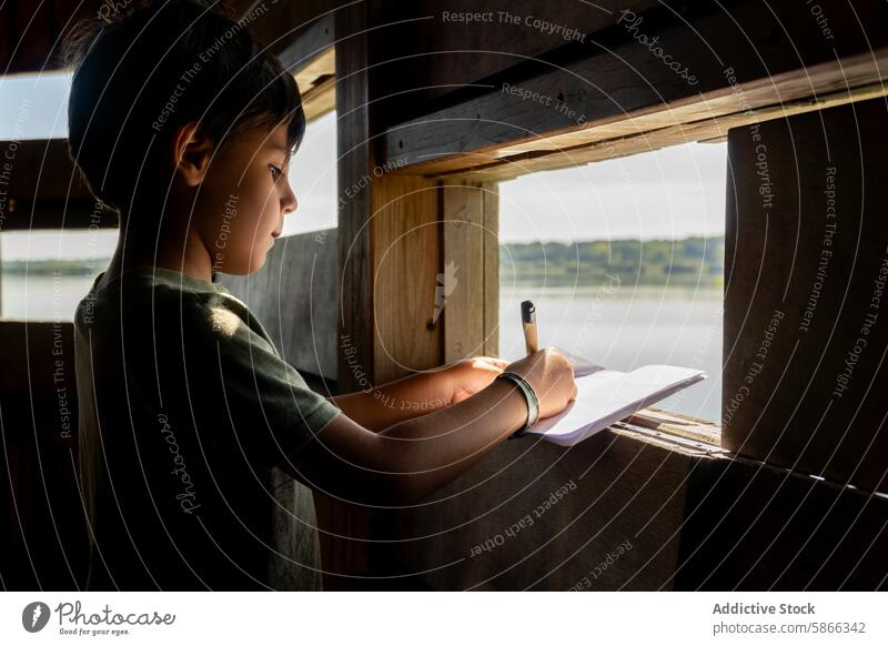 Young boy taking notes in a birdwatching hide nature notebook pen writing observing side view lake serene wooden structure observation wildlife education