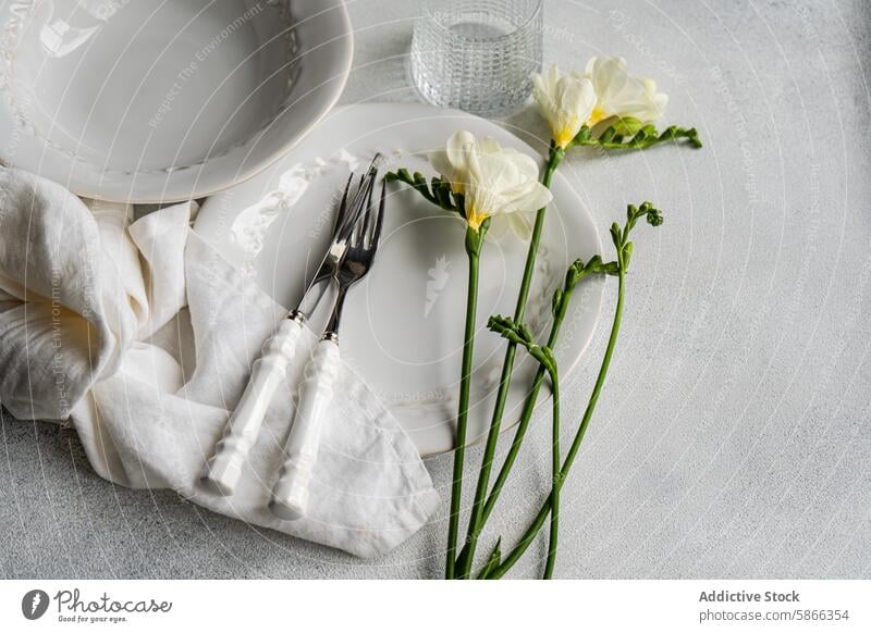 Elegant Freesia-themed table setting with white and silver accents freesia flower elegant plate cutlery napkin delicate sophisticated linen fabric texture decor