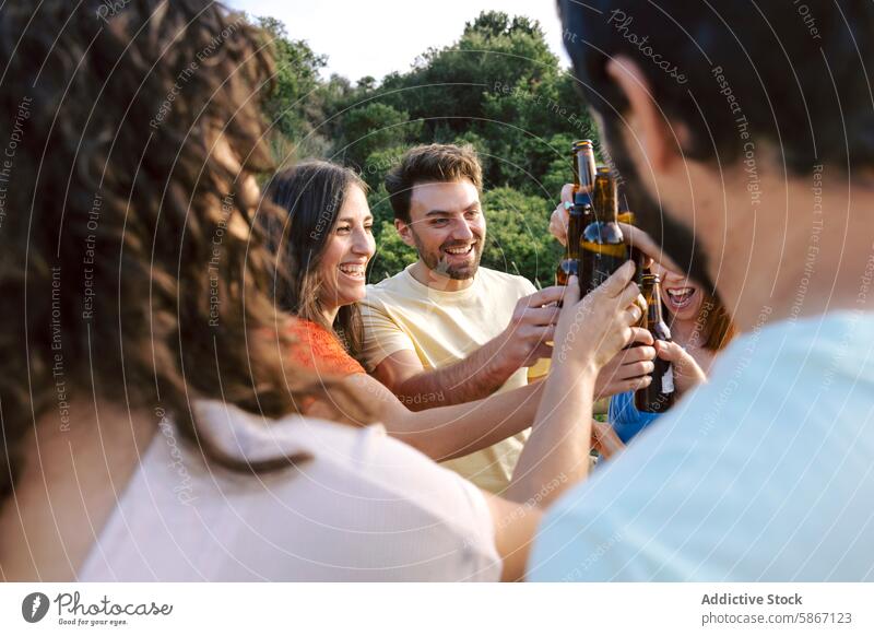 Group of Friends Toasting with Beers Outdoors at a Celebration friend group toast beer outdoors celebration nature cheerful happy gathering party social summer