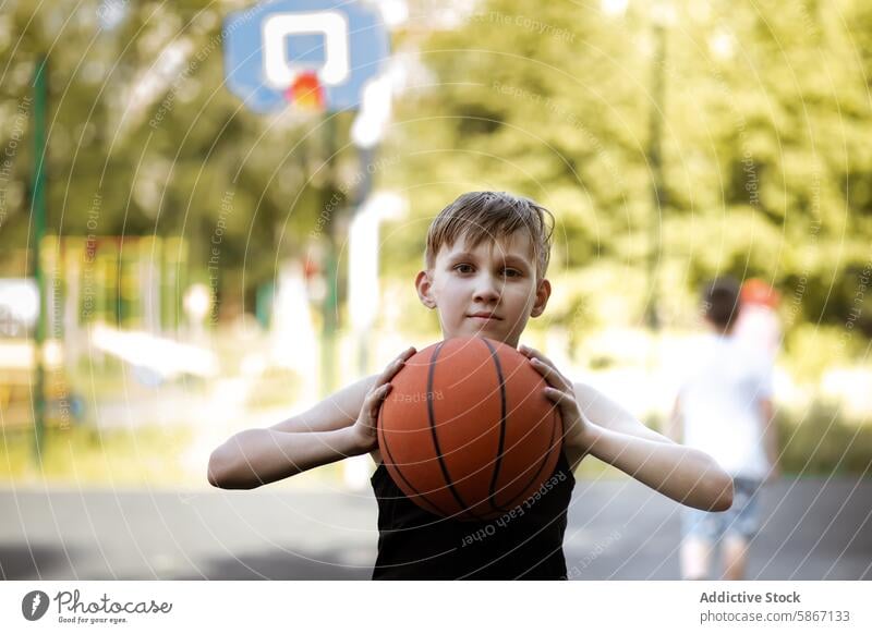 Young boy holding a basketball at an outdoor court teenager sport summer active leisure game play fitness healthy recreation youth focus sunshine nature park