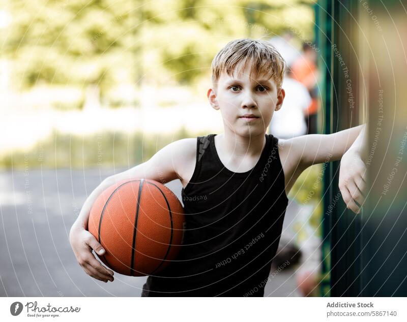 Young Boy with a basketball on an outdoor court on a sunny day boy teenager young sporty game summer youth athlete active recreation playground sports fitness