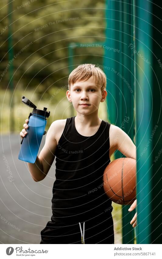 Young Boy with Basketball and Water Bottle on Outdoor Court boy teenager basketball outdoor court young sporty game summer youth athlete active recreation