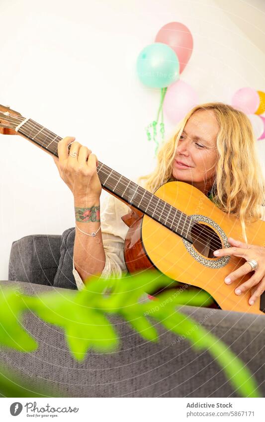 Senior woman enjoying guitar music at a colorful indoor celebration senior balloon happiness party festivity casual fun elderly intimate guitar playing musician