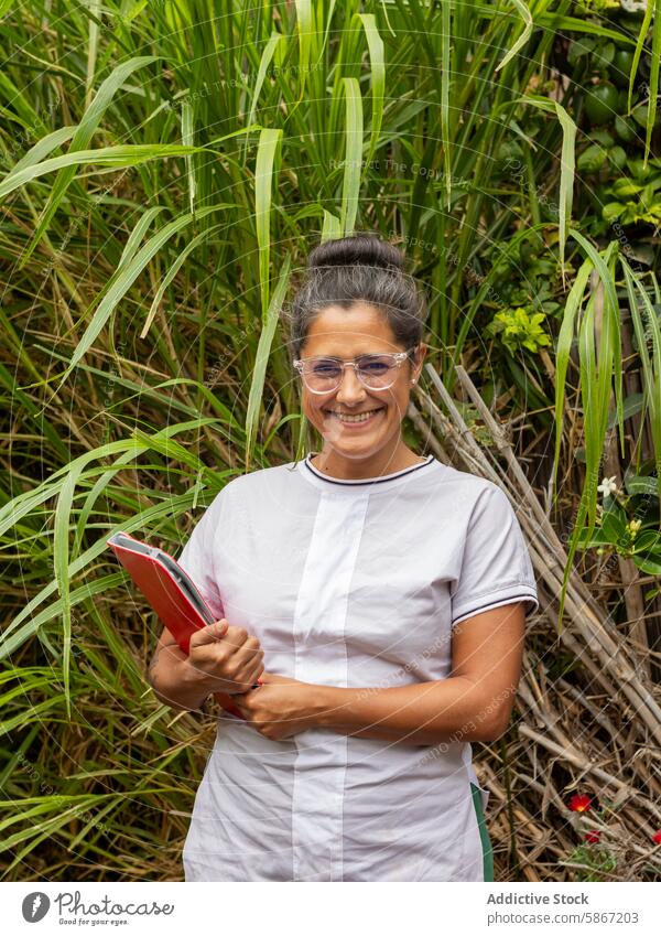 Female veterinarian smiling with tablet in lush greenery female camera uniform gadget professional cheerful woman device healthcare animal care outdoor nature