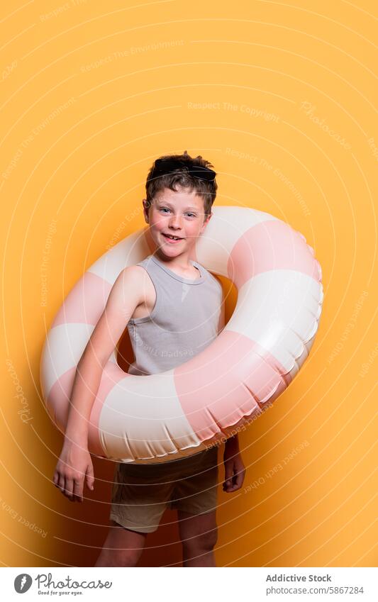 Boy with swim ring on yellow background ready for summer child boy studio smile cheerful tank top shorts sunglasses fun happy water holiday vacation playful