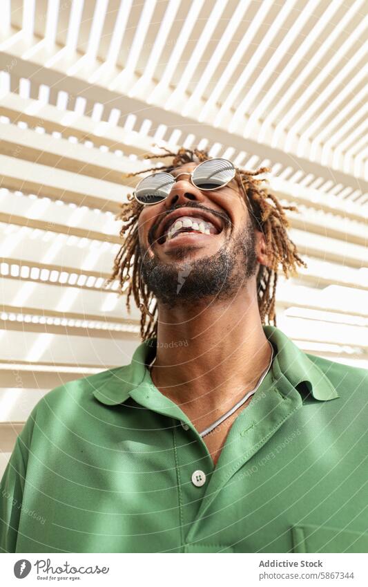 Joyful African American man smiling in summer sunlight african american joyful sunglasses dreadlocks laughing green shirt stylish outdoor sunlit happiness