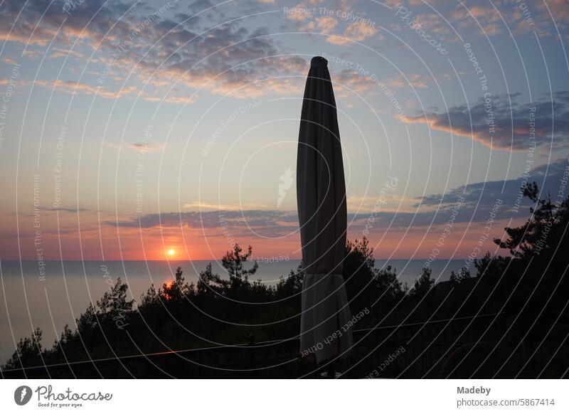 View from the terrace with parasol of a romantic sunset with lush vegetation and clouds over the Black Sea in Inkumu in the province of Bartin in Turkey coast