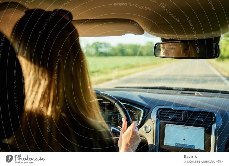 Woman driving car on country road. Back view of female driver in vehicle woman hand auto sunset travel journey steering wheel dashboard back view sunlight
